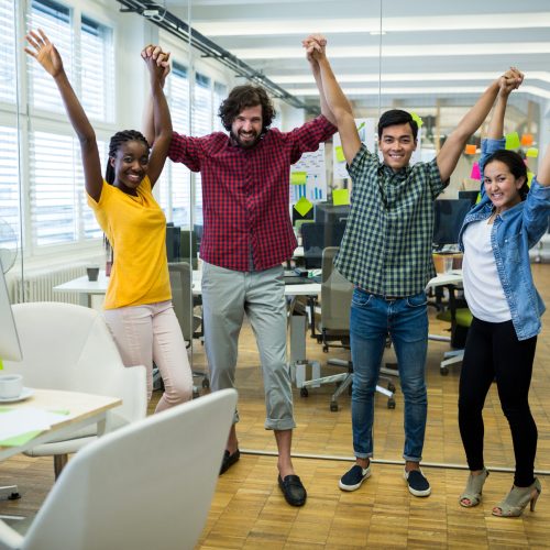 Portrait of business executives raising arms in office